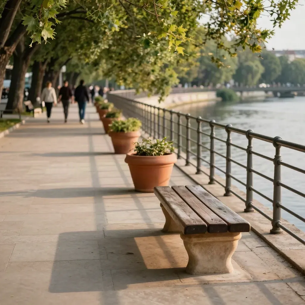 Riverside promenade with split paths, planters, benches, and long evening shadows.